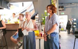 Zwei Frauen aus dem Vorstand des Kreisverbands – eine mit weißem Oberteil, die andere mit blauer Bluse – stehen nebeneinander vor dem Publikum und begrüßen die Gäste.