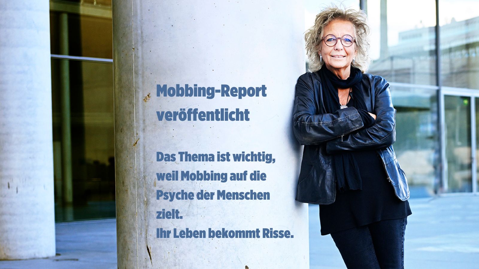 Beate Müller-Gemmeke, Bundestagsabgeordnete von Bündnis 90/Die Grünen, lehnt mit verschränkten Armen an einer Betonwand. Sie trägt eine schwarze Lederjacke, eine Brille und hat blonde, lockige Haare. Sie lächelt selbstbewusst in die Kamera. Daneben steht in blauer Schrift: 'Mobbing-Report veröffentlicht! Das Thema ist wichtig, weil Mobbing auf die Psyche der Menschen zielt. Ihr Leben bekommt Risse.' Der Hintergrund ist modern und urban."