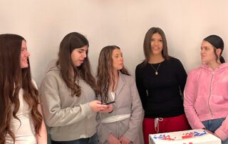 Junge Frauen bei der Veranstaltung von gÖrls e.V. im Gespräch – selbstbewusst, konzentriert, in solidarischer Atmosphäre. Im Vordergrund ein bemalter Karton mit dem Schriftzug „görls e.V.“.