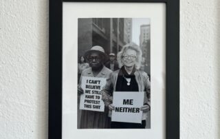 Schwarz-Weiß-Fotocollage einer Demonstrationsszene: Links eine ältere Frau mit Protestschild „I can’t believe we still have to protest this shit“. Rechts daneben Beate Müller-Gemmeke, eingefügt ins Bild, lachend mit Schild „Me neither“.