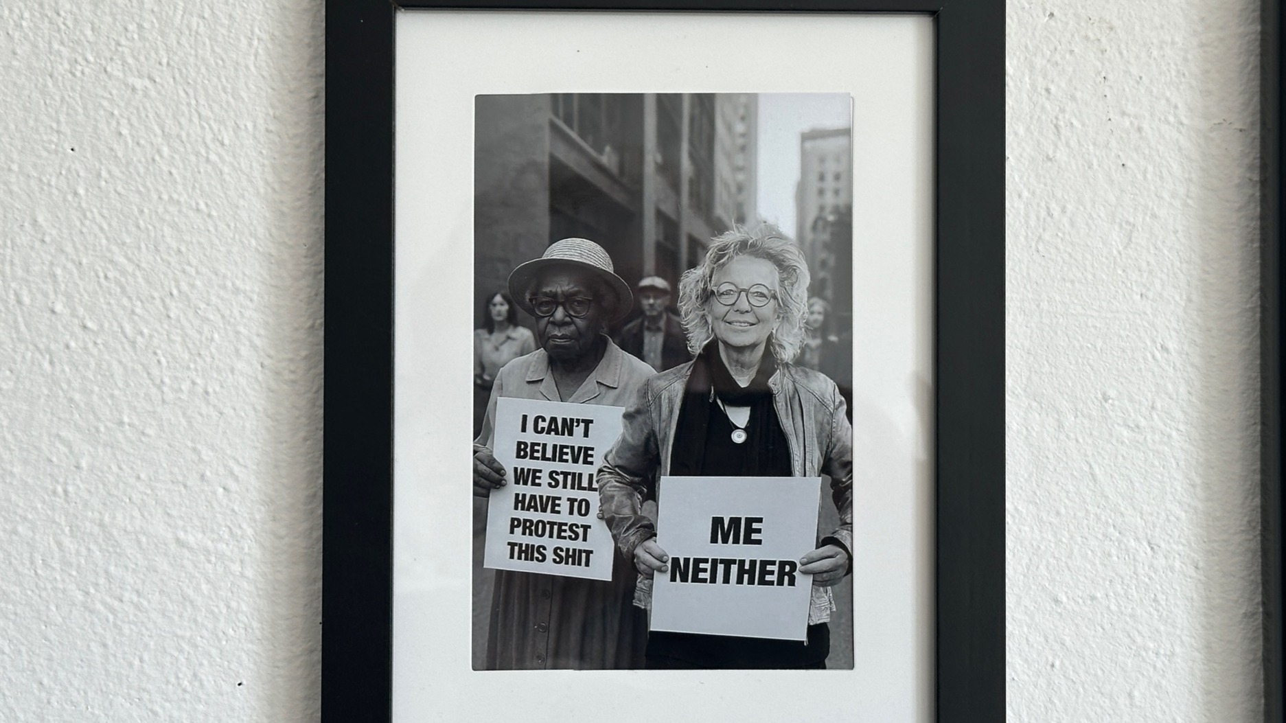 Schwarz-Weiß-Fotocollage einer Demonstrationsszene: Links eine ältere Frau mit Protestschild „I can’t believe we still have to protest this shit“. Rechts daneben Beate Müller-Gemmeke, eingefügt ins Bild, lachend mit Schild „Me neither“.