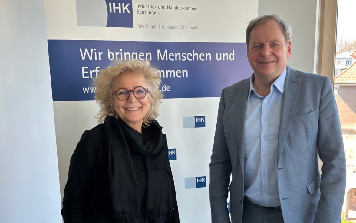Beate Müller-Gemmeke steht neben einem Mann in Anzug vor einem Roll-up der Industrie- und Handelskammer Reutlingen mit dem Schriftzug „Wir bringen Menschen und Erfolge zusammen“. Beide lächeln in die Kamera.