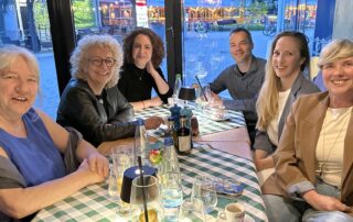 Beate Müller-Gemmeke beim Abschiedsessen mit ihrem Reutlinger Wahlkreisteam an einem gedeckten Tisch in einem Restaurant – sechs Personen lächeln in die Kamera, im Hintergrund die nächtliche Innenstadt von Reutlingen.