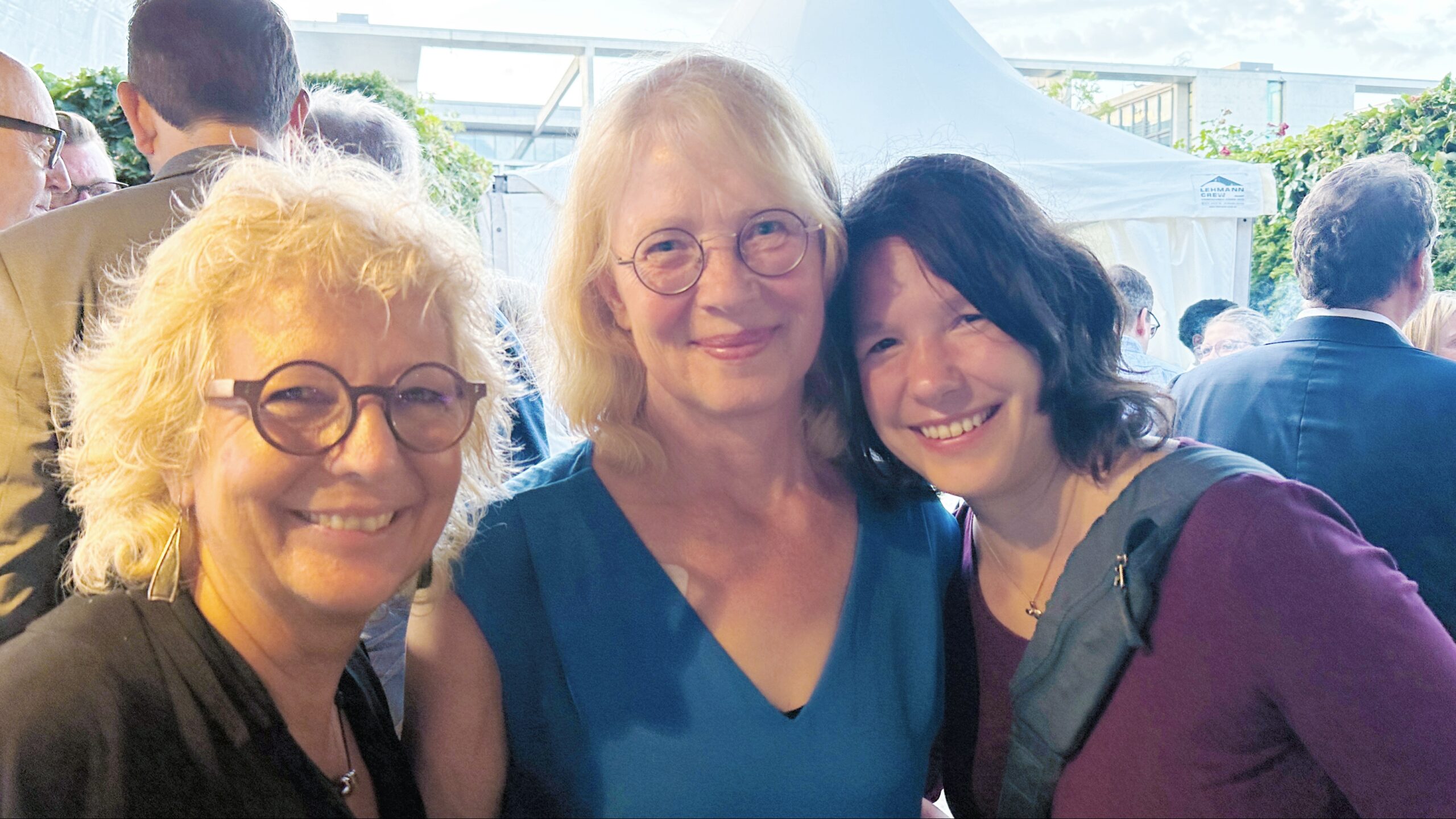 Beate Müller-Gemmeke mit Tabea Rößner (ehemalige MdB, Bündnis 90/Die Grünen) und Linda Heitmann (MdB, Bündnis 90/Die Grünen) beim Sommerfest der Deutschen Parlamentarischen Gesellschaft. Alle drei lächeln in die Kamera, im Hintergrund ein weißes Zelt.