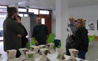 Beate Müller-Gemmeke im Kultspace Münsingen vor einem Ausstellungstisch – sie spricht mit zwei Begleitern über die Kunstwerke der Demokratie-Ausstellung.