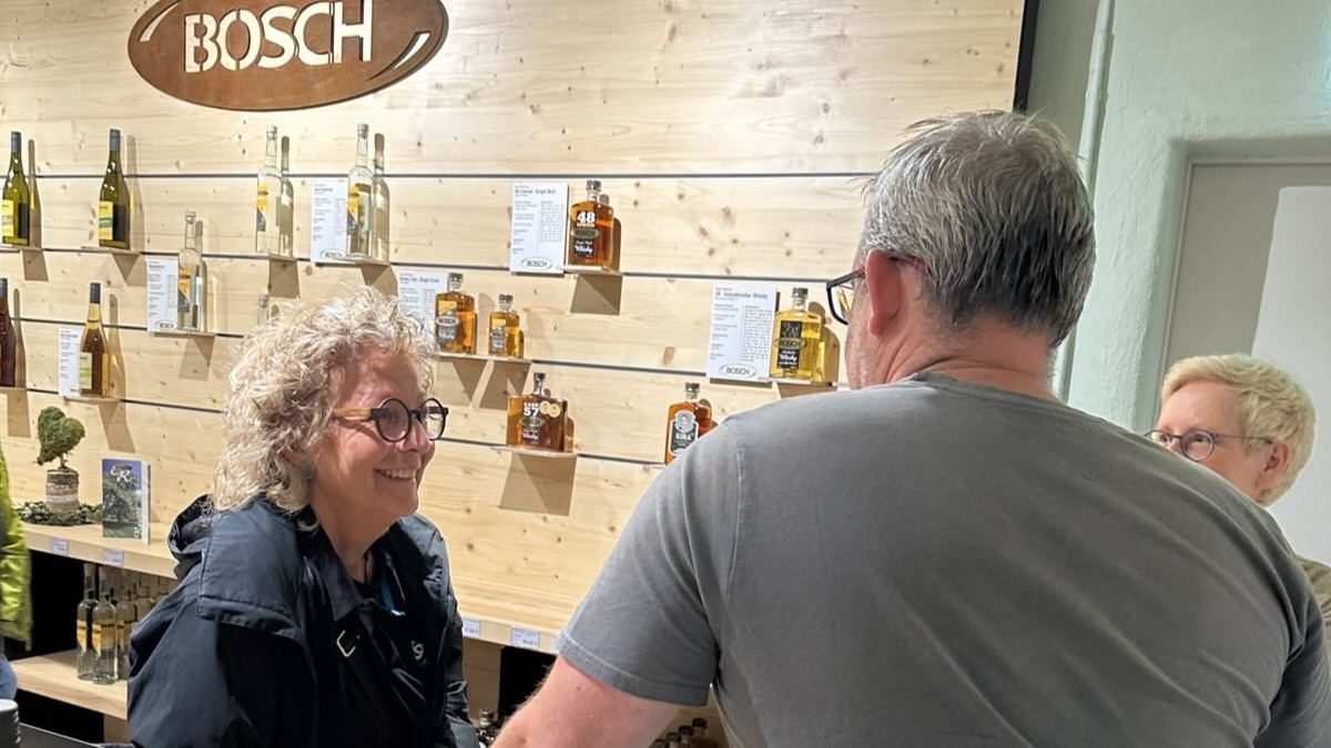 Beate Müller-Gemmeke im Gespräch vor einem Regal mit regionalen Whiskeysorten in einer Manufaktur im Albgut Münsingen.