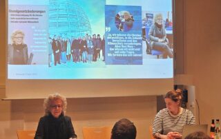 Beate Müller-Gemmeke bei der Kreisversammlung der Grünen Reutlingen. Sie berichtet vor interessiertem Publikum über die jüngsten Bundestagsentscheidungen zur Schuldenbremse und zum Sondervermögen. Im Hintergrund eine Präsentation mit Zitaten und Fotos aus dem Bundestag.