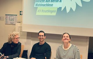 Beate Müller-Gemmeke gemeinsam mit zwei Parteikolleg:innen bei der Kreisversammlung der Reutlinger Grünen. Im Hintergrund die Projektion: „Bericht aus Berlin & Wahlnachlese“. Die Atmosphäre ist offen und konzentriert.