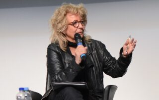 Beate Müller-Gemmeke spricht auf einer Veranstaltung ins Mikrofon und gestikuliert mit einem Stift in der Hand.