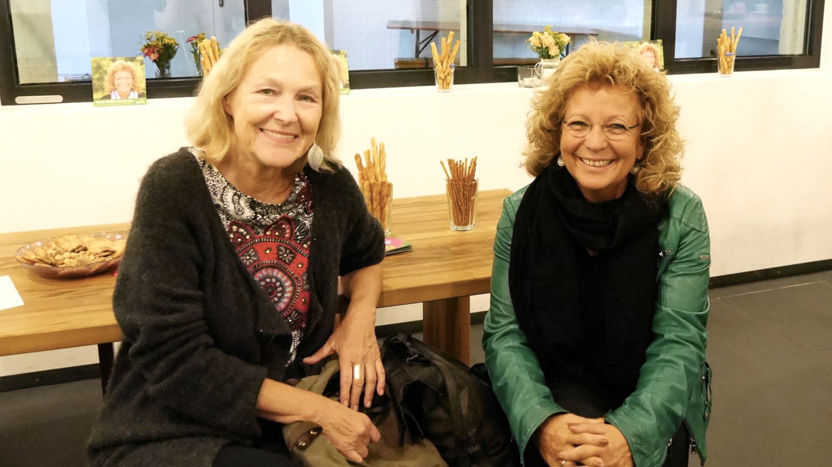 Beate Müller-Gemmeke und Sylvia Kotting-Uhl sitzen nebeneinander an einem Tisch und lächeln in die Kamera.