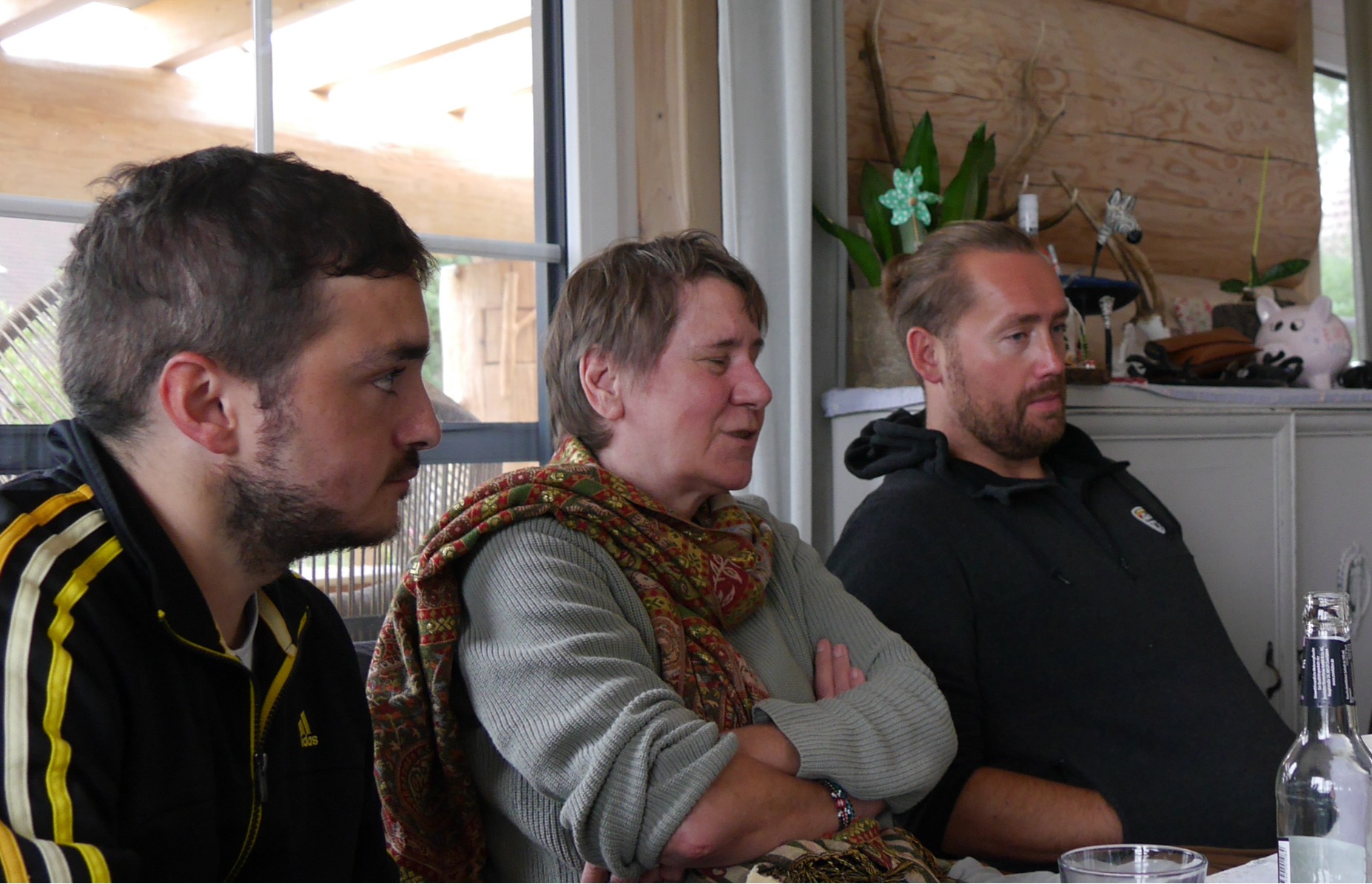 Niklas, Karin und Christian sitzen an einem Tisch und hören aufmerksam zu.