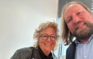 Selfie von Beate Müller-Gemmeke mit Toni Hofreiter. Beide lächeln in die Kamera. Beate trägt eine schwarze Lederjacke und Schal, Toni Hofreiter ein Sakko mit Hemd.