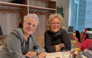 Beate Müller-Gemmeke im Gespräch mit Sylvia Rietenberg beim Treffen im Bundestag. Beide sitzen an einem Tisch, lächeln in die Kamera und wirken konzentriert und zugewandt.