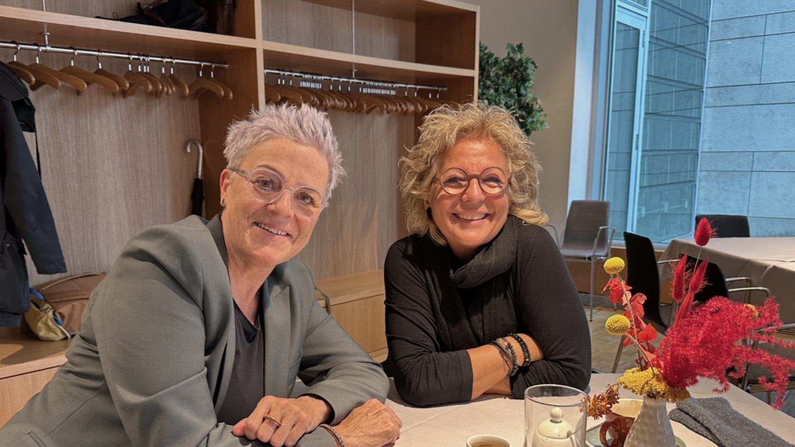Beate Müller-Gemmeke im Gespräch mit Sylvia Rietenberg beim Treffen im Bundestag. Beide sitzen an einem Tisch, lächeln in die Kamera und wirken konzentriert und zugewandt.