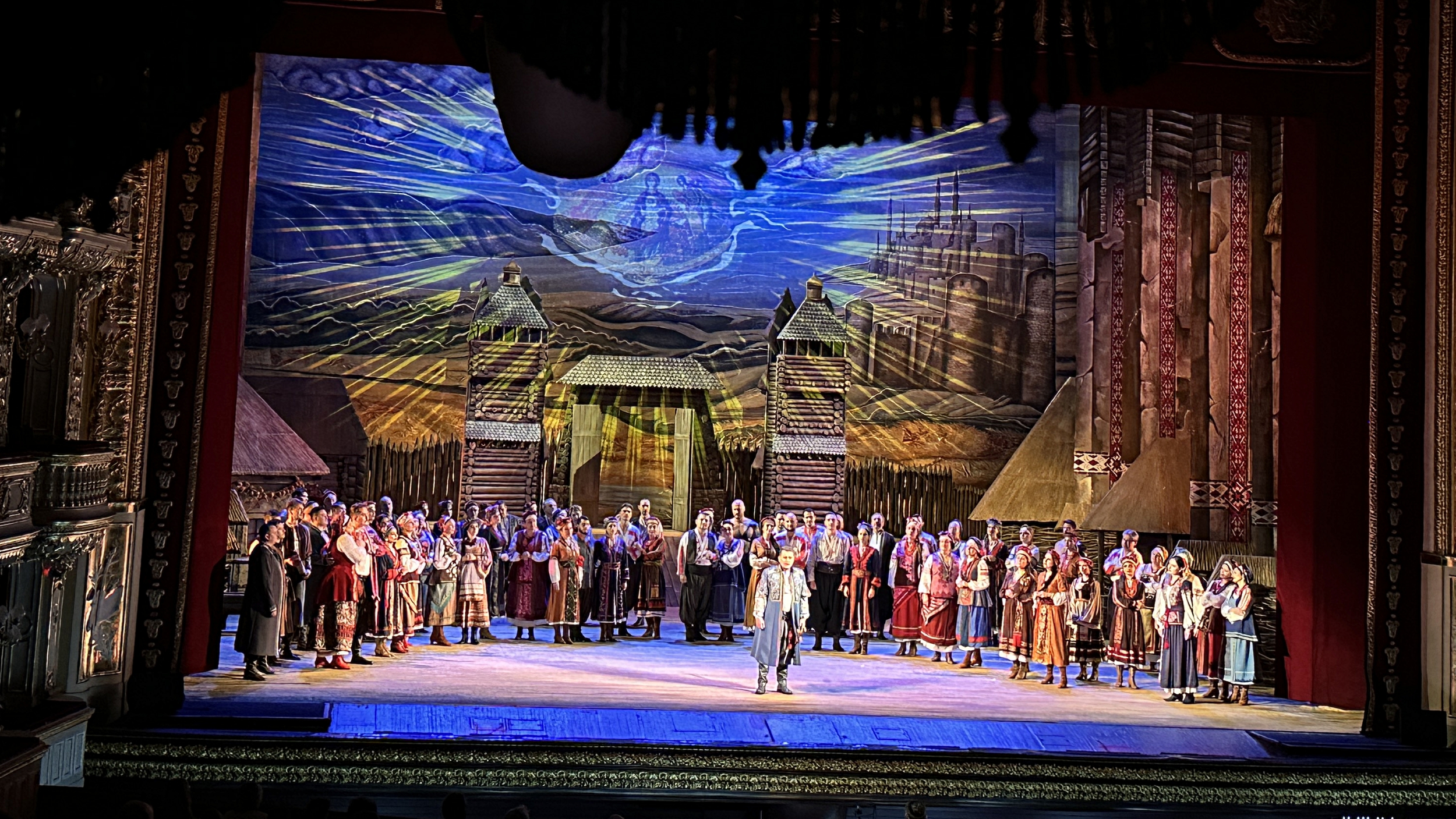Ensemble auf der Bühne der Oper Odessa bei einer Premiere – traditionelle Kostüme, leuchtendes Bühnenbild, starke Farben und Emotionen.