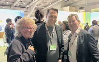 Beate Müller-Gemmeke steht auf der BDK in Hannover neben Kai Keune und Christoph Schmitz-Dethlefsen (ver.di-Bundesvorstand). Alle drei tragen Delegierten-Badges und lächeln in die Kamera. Im Hintergrund sind Messewände und weitere Besucher:innen sichtbar.
