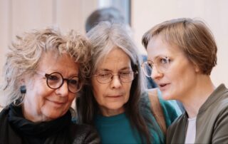 Beate Müller-Gemmeke steht mit zwei weiteren Teilnehmerinnen in der Halle des Landesparteitags im Gespräch, rechts im Bild ist Franziska Brantner zu sehen.