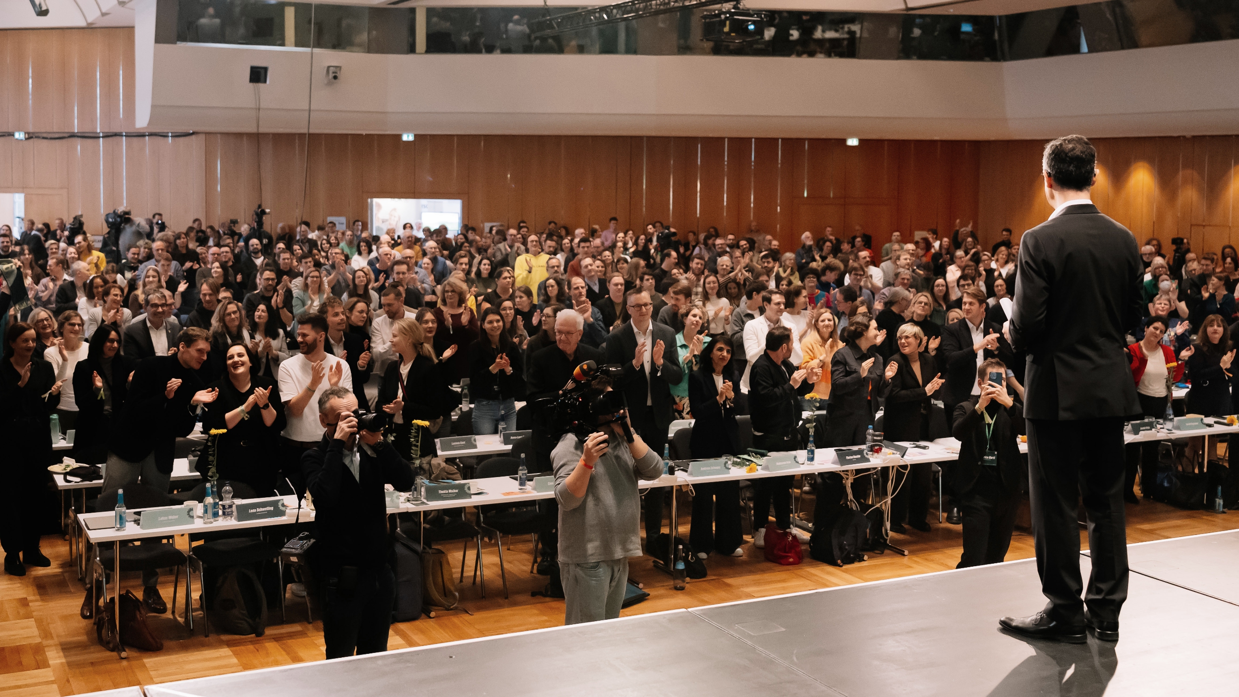 Cem Özdemir steht auf der Bühne des Landesparteitags und blickt in eine voll besetzte Halle, viele Delegierte stehen und applaudieren.
