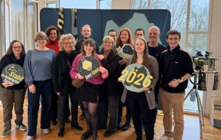 Beate Müller-Gemmeke steht mit Mitgliedern aus Reutlingen vor einer grünen Kulisse, mehrere Personen halten Schilder mit Aufschriften wie Klimaschutz und 2026.