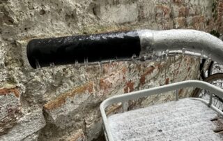 Vereister Lenker eines Fahrrads vor einer Backsteinmauer in Berlin. Kleine Eiszapfen am Lenker sind zu sehen - Detailbild der klirrenden Kälte.