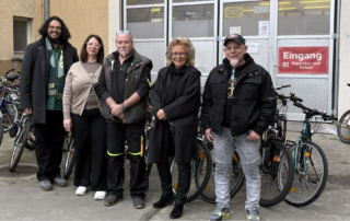 Gruppenfoto vor der Fahrrad-Werkstatt Geislingen: Julian Beier, Mitarbeitende der Werkstatt und Beate Müller-Gemmeke stehen gemeinsam vor dem Eingang „Reparatur und Verkauf“.