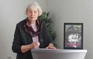 Bettina Noack steht an einem Rednerpult im Mütter- und Nachbarschaftszentrum Reutlingen und spricht bei der Verleihung des Irmgard-Zecher-Preises. Neben ihr steht ein gerahmtes Bild von Irmgard Zecher mit der Aufschrift „Irmgard-Zecher-Preis 2026 – Bettina Noack“.