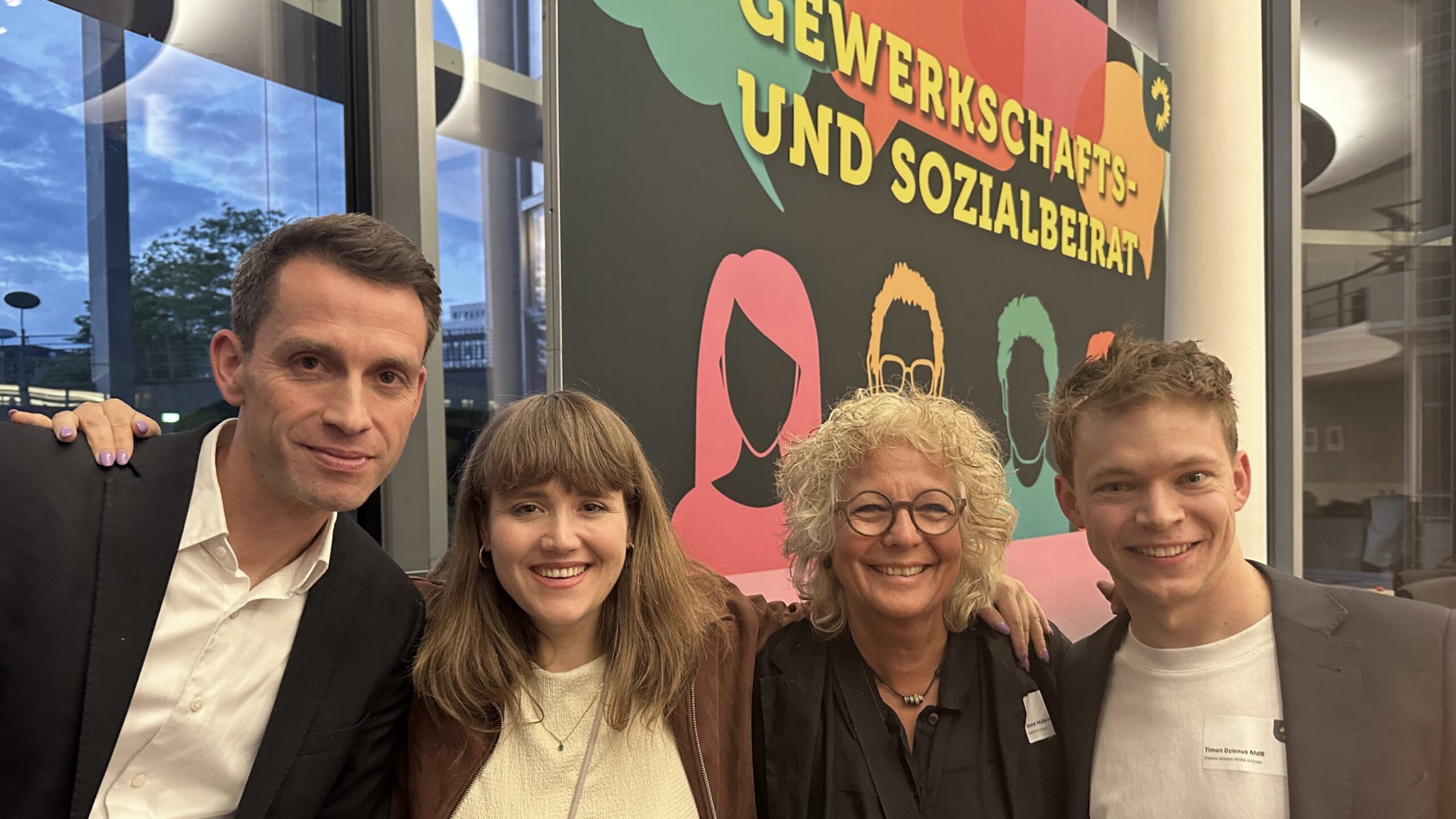 Gruppenfoto vor einer großen bunten Wand mit der Aufschrift „Gewerkschafts- und Sozialbeirat“. Zu sehen sind Andreas Audretsch, Ricarda Lang, Beate Müller-Gemmeke und Timon Dzienus. Alle lächeln in die Kamera.