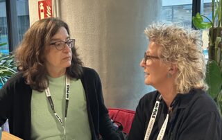 Ute Kratzmeier, Sprecherin von GewerkschaftsGrün Baden-Württemberg, und Beate Müller-Gemmeke sitzen an einem Tisch und tauschen sich intensiv aus. Auf dem Tisch liegen Unterlagen und Informationsmaterialien.