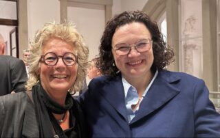Andrea Nahles und Beate Müller-Gemmeke stehen beim BA-Empfang im Bundestag eng nebeneinander und lächeln in die Kamera. Andrea Nahles trägt einen dunkelblauen Blazer über einer hellblauen Bluse, Beate Müller-Gemmeke schwarze Kleidung.